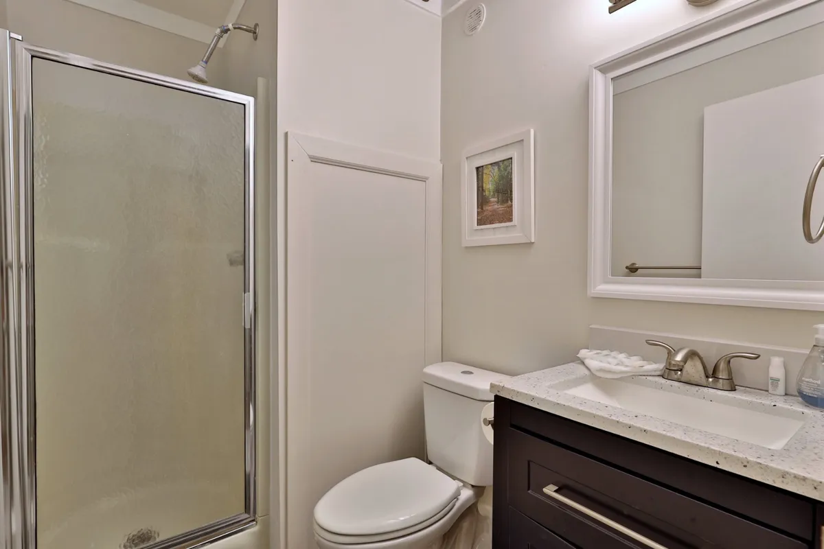 A clean, modern bathroom with a spacious shower, a stylish vanity, and a well-lit mirror. The room is bathed in soft, inviting light—perfect for refreshing mornings or winding down after a long day outdoors.
