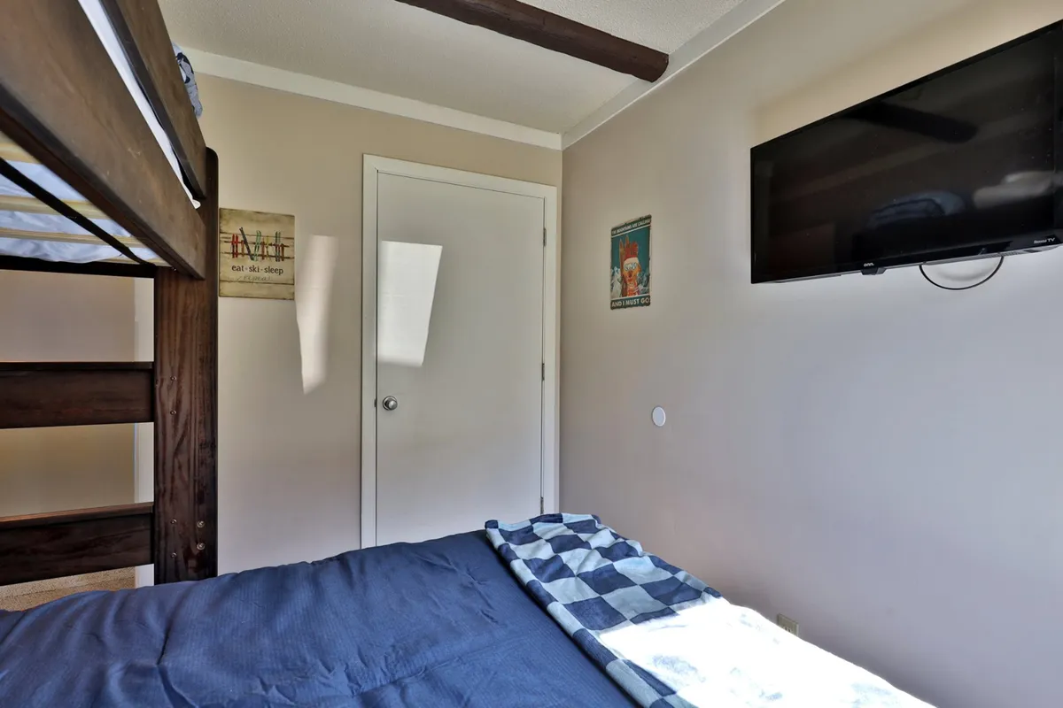 This interior shot highlights a dedicated bunk bed room with wall art and a television, capturing a cozy and relaxed setting for children. The layout features a safety ladder, aligning with the section's note about bunk bed safety.