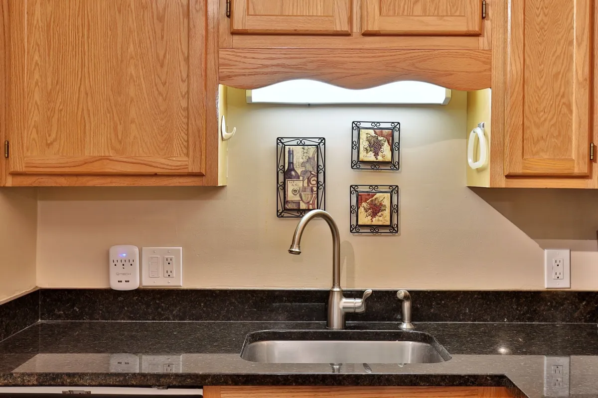 This image showcases a warm, welcoming kitchen space with a kitchen sink, decorative wall art, and cabinetry, suggesting an inviting area for meal preparation and family gatherings.